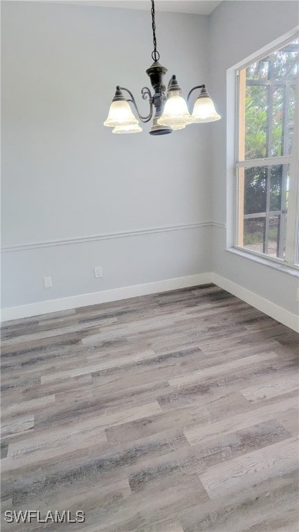 empty room with a notable chandelier and hardwood / wood-style floors