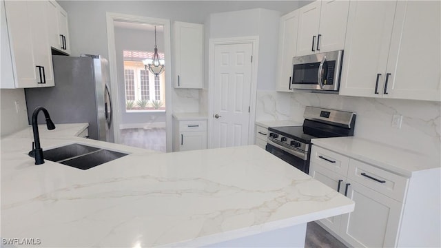 6733 Bent Grass Dr, Naples, FL 34113 - kitchen with decorative backsplash, stainless steel appliances, white cabinetry, a sink, and an inviting chandelier
