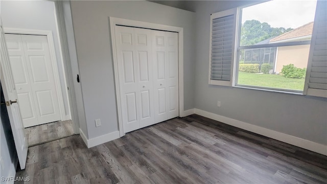 unfurnished bedroom with dark wood-type flooring and a closet