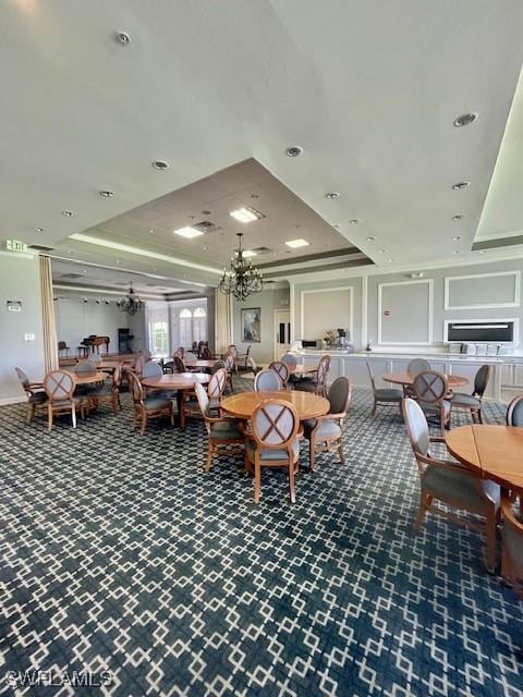 dining area featuring a chandelier, carpet flooring, and a raised ceiling