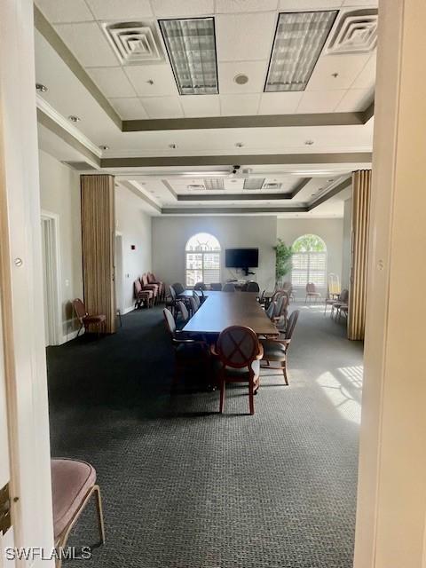 carpeted dining space with visible vents and a tray ceiling