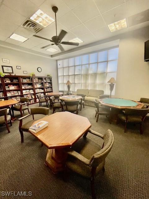 game room with a paneled ceiling, carpet, visible vents, and a ceiling fan