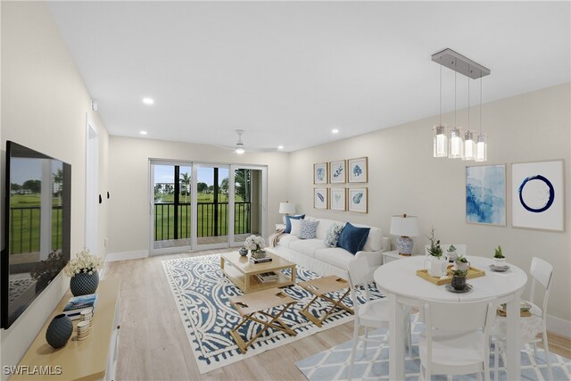 living room featuring ceiling fan with notable chandelier and light wood-type flooring