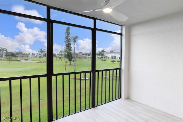 unfurnished sunroom with view of golf course and a ceiling fan