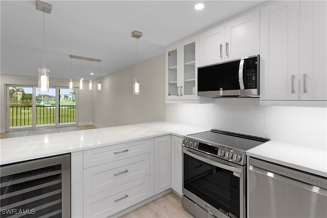 kitchen featuring beverage cooler, glass insert cabinets, stainless steel appliances, light countertops, and white cabinetry