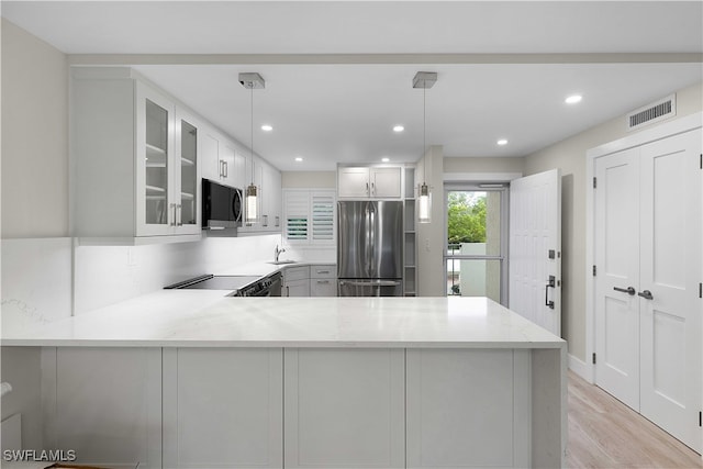 kitchen with stainless steel appliances, visible vents, glass insert cabinets, a sink, and a peninsula