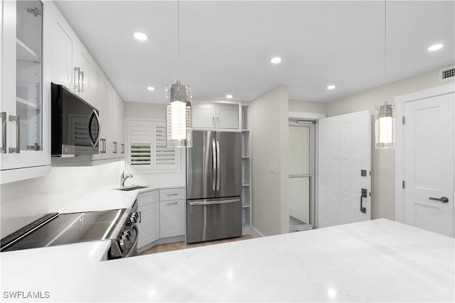 kitchen with recessed lighting, range with electric cooktop, a sink, and freestanding refrigerator