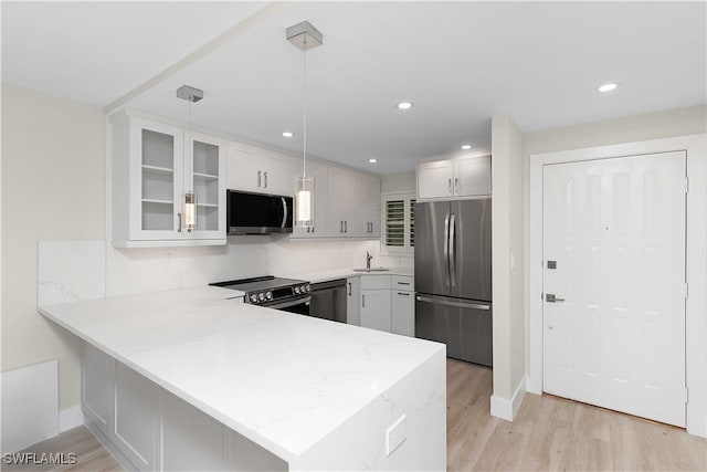 kitchen featuring a peninsula, appliances with stainless steel finishes, light wood-type flooring, and glass insert cabinets