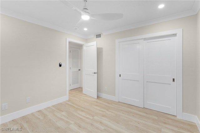 unfurnished bedroom with a closet, visible vents, light wood-style flooring, ornamental molding, and baseboards