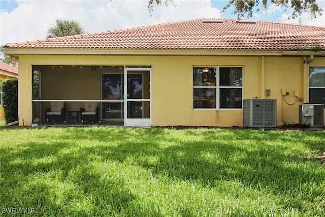 rear view of house with a lawn and central AC