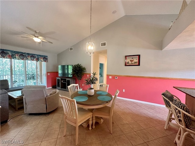 tiled dining space with high vaulted ceiling and ceiling fan with notable chandelier