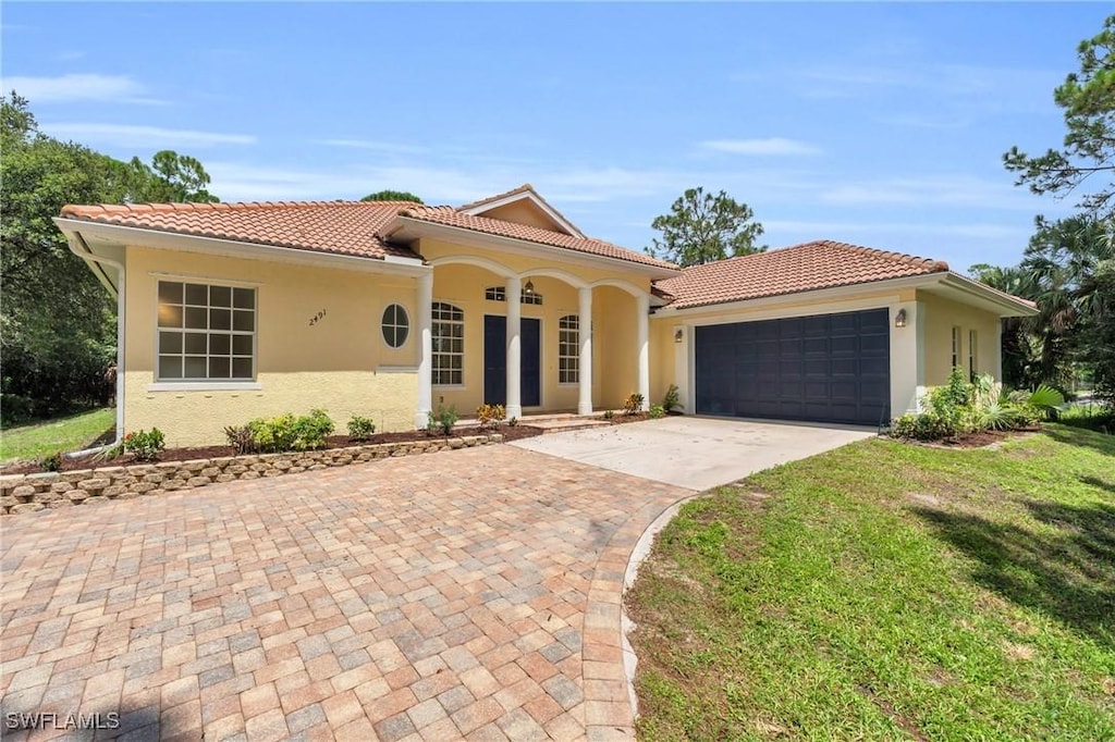 mediterranean / spanish house featuring a garage and a front yard