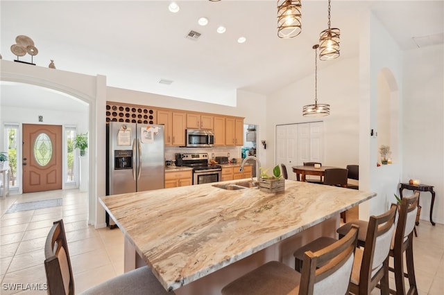 kitchen with pendant lighting, sink, a kitchen breakfast bar, a center island with sink, and appliances with stainless steel finishes