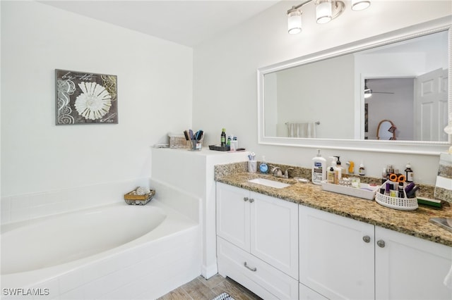 bathroom featuring tiled tub, vanity, hardwood / wood-style flooring, and ceiling fan