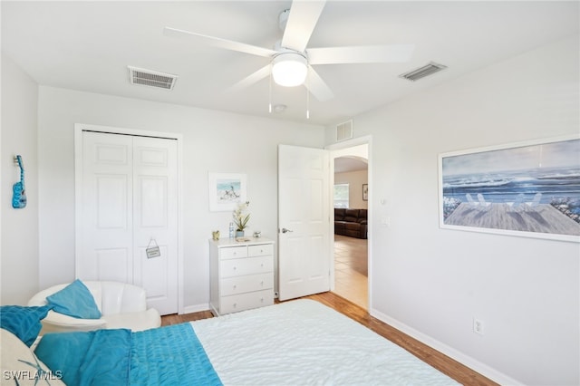 bedroom with light hardwood / wood-style flooring, ceiling fan, and a closet