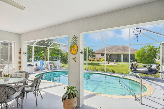 view of pool with glass enclosure, a lawn, and a patio