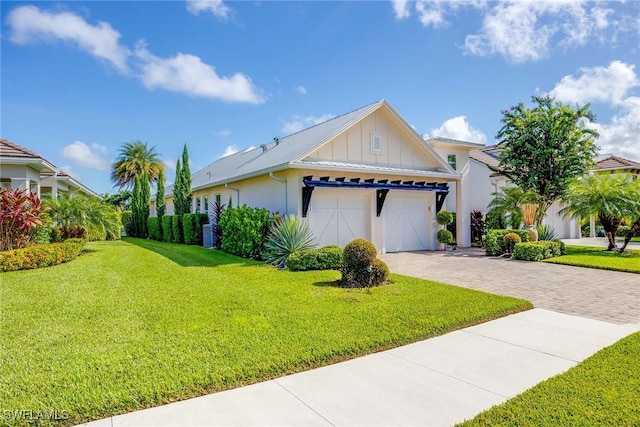 view of front of home featuring metal roof, an attached garage, decorative driveway, board and batten siding, and a front yard