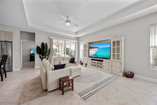 14151 Nautica Ct, Naples, FL 34114 - living room featuring a ceiling fan, a raised ceiling, baseboards, and light tile patterned floors