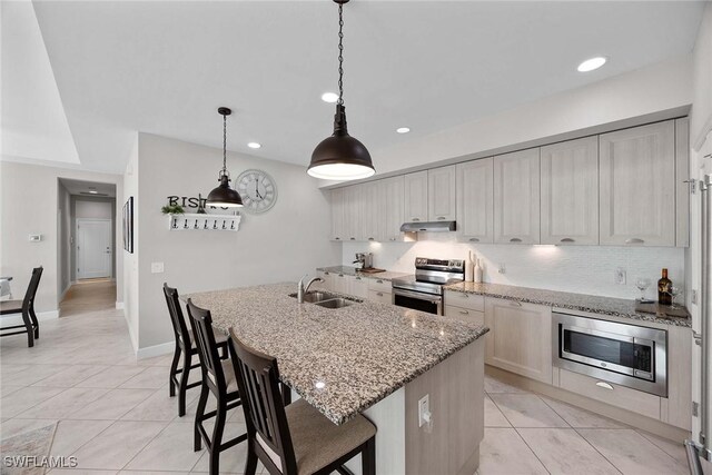 14151 Nautica Ct, Naples, FL 34114 - kitchen featuring tasteful backsplash, a center island with sink, stainless steel appliances, under cabinet range hood, and a sink