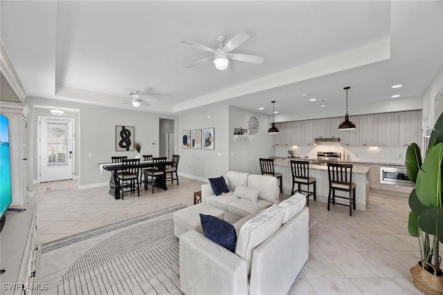 14151 Nautica Ct, Naples, FL 34114 - living room featuring light tile patterned floors, a tray ceiling, and baseboards
