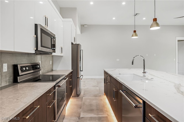 kitchen featuring pendant lighting, backsplash, stainless steel appliances, sink, and white cabinetry