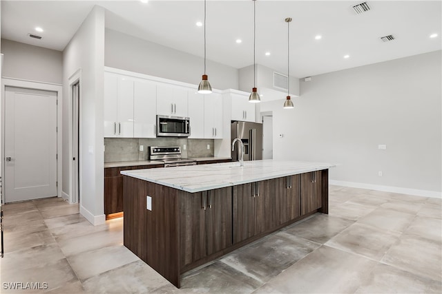 kitchen with a spacious island, stainless steel appliances, light stone countertops, and backsplash