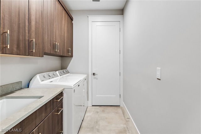 clothes washing area featuring cabinets and washer and dryer