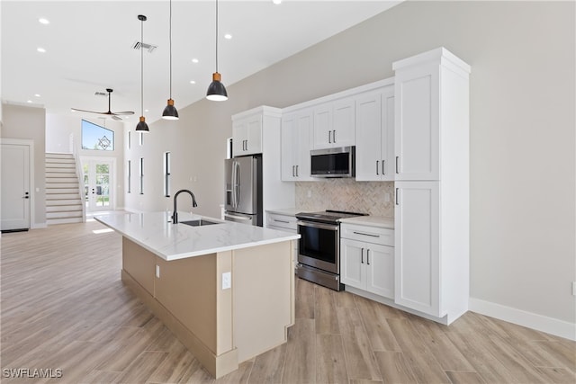 kitchen with pendant lighting, white cabinetry, appliances with stainless steel finishes, and a kitchen island with sink