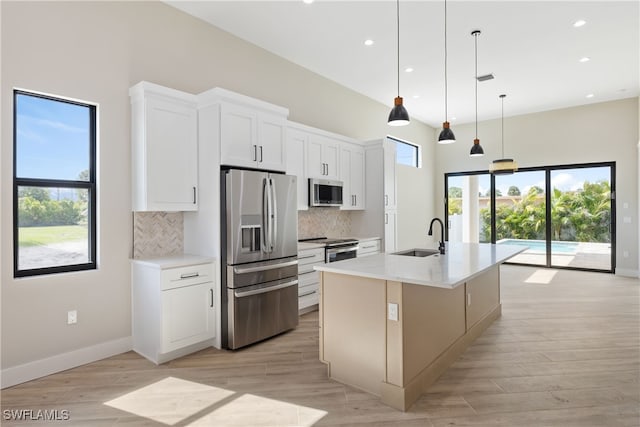 kitchen featuring decorative light fixtures, an island with sink, white cabinetry, and stainless steel appliances