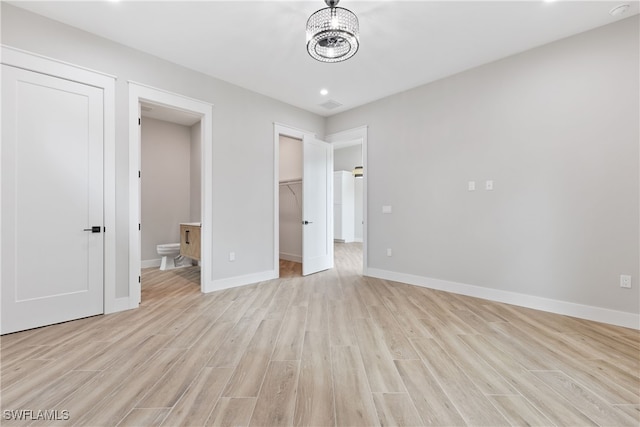 unfurnished bedroom with light hardwood / wood-style flooring, a spacious closet, and ensuite bathroom