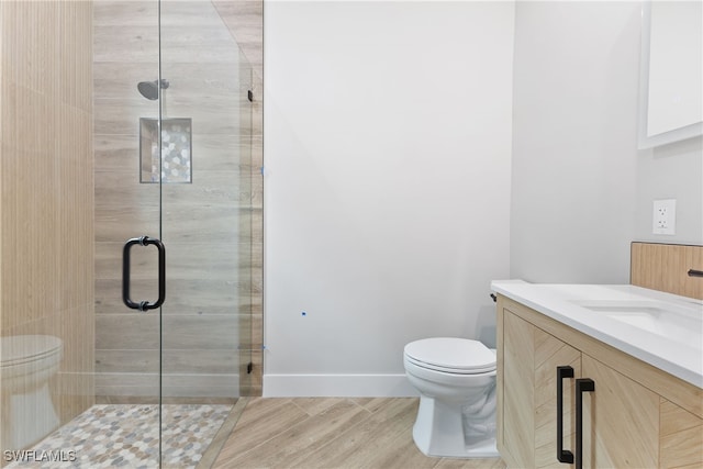 bathroom featuring a shower with shower door, toilet, and vanity