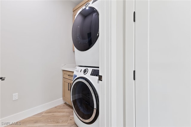 washroom featuring cabinets and stacked washer and dryer