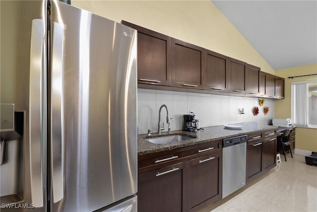 kitchen featuring lofted ceiling, dark stone counters, sink, tasteful backsplash, and stainless steel appliances