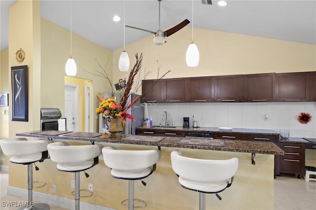 kitchen featuring decorative backsplash, sink, pendant lighting, a breakfast bar area, and light tile patterned flooring