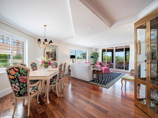 dining area featuring dark wood-type flooring, ornamental molding, and a notable chandelier