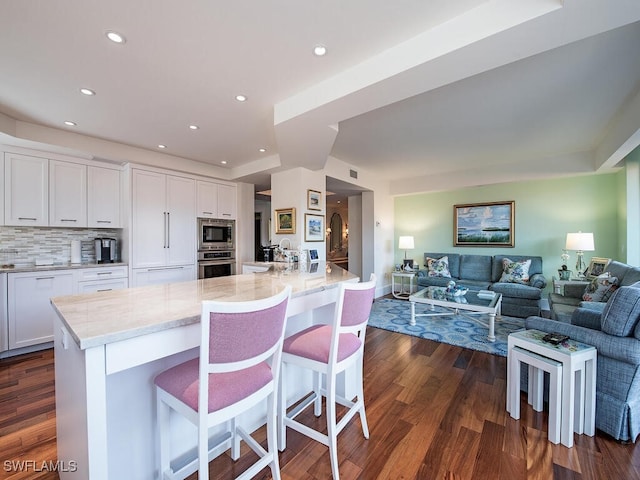 kitchen with dark wood-type flooring, open floor plan, white cabinetry, and stainless steel appliances