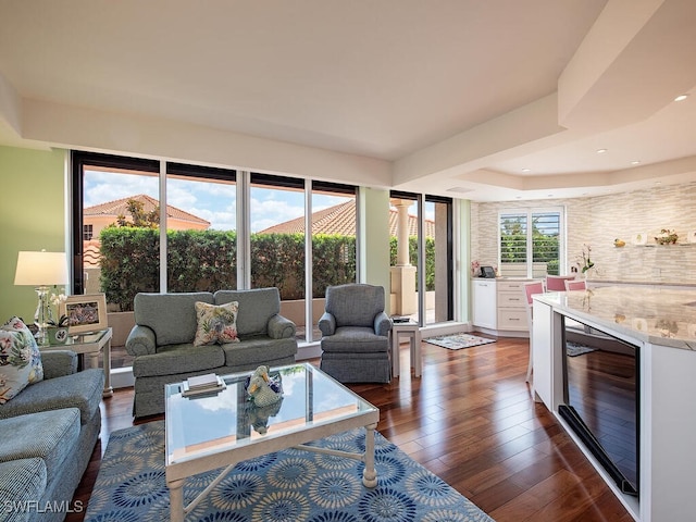 living room featuring a tray ceiling, dark hardwood / wood-style floors, and wine cooler