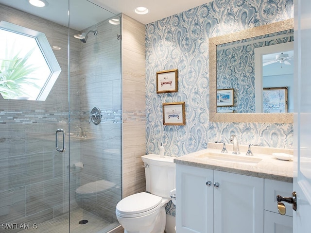 bathroom with vanity, toilet, an enclosed shower, and ceiling fan