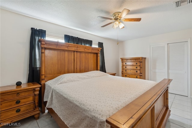 tiled bedroom with a textured ceiling, a closet, and ceiling fan