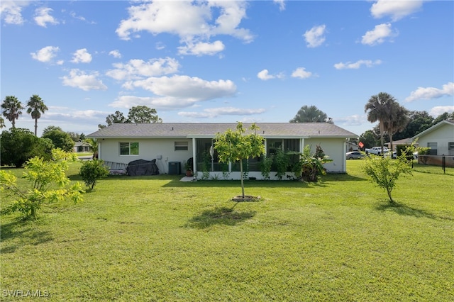 rear view of house featuring a lawn and a sunroom