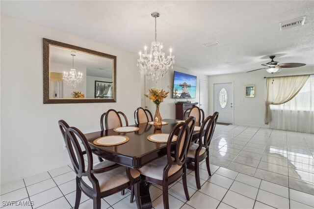 dining space with a textured ceiling, a wealth of natural light, light tile patterned flooring, and ceiling fan with notable chandelier