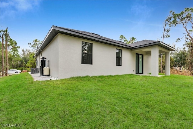 back of house with central AC and a lawn