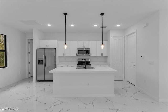 kitchen featuring decorative light fixtures, stainless steel appliances, an island with sink, white cabinetry, and sink