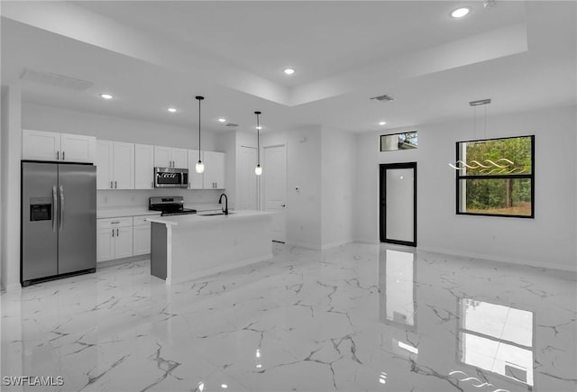 kitchen with white cabinets, a center island with sink, appliances with stainless steel finishes, and hanging light fixtures