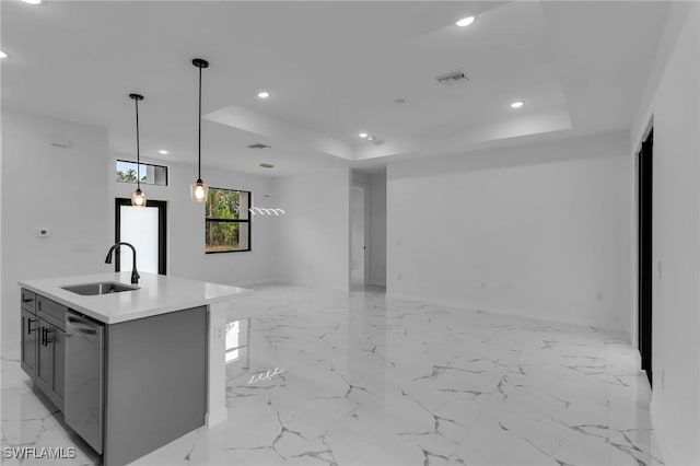 kitchen featuring decorative light fixtures, a center island with sink, a raised ceiling, and sink