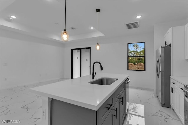 kitchen featuring sink, white cabinets, stainless steel refrigerator, and pendant lighting