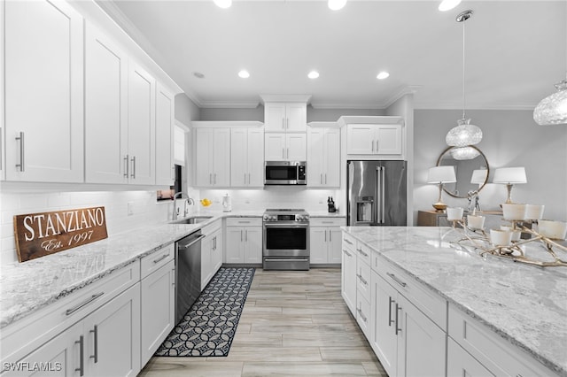 kitchen with white cabinets, decorative backsplash, ornamental molding, stainless steel appliances, and a sink