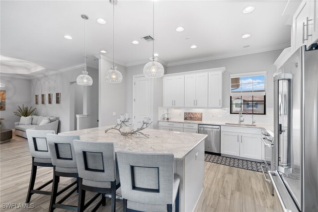 kitchen with light stone countertops, white cabinetry, hanging light fixtures, stainless steel appliances, and a breakfast bar