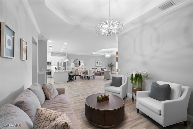 living room with a chandelier, visible vents, ornamental molding, light wood finished floors, and a raised ceiling