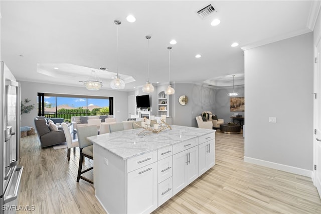 kitchen with a center island, visible vents, open floor plan, and a raised ceiling